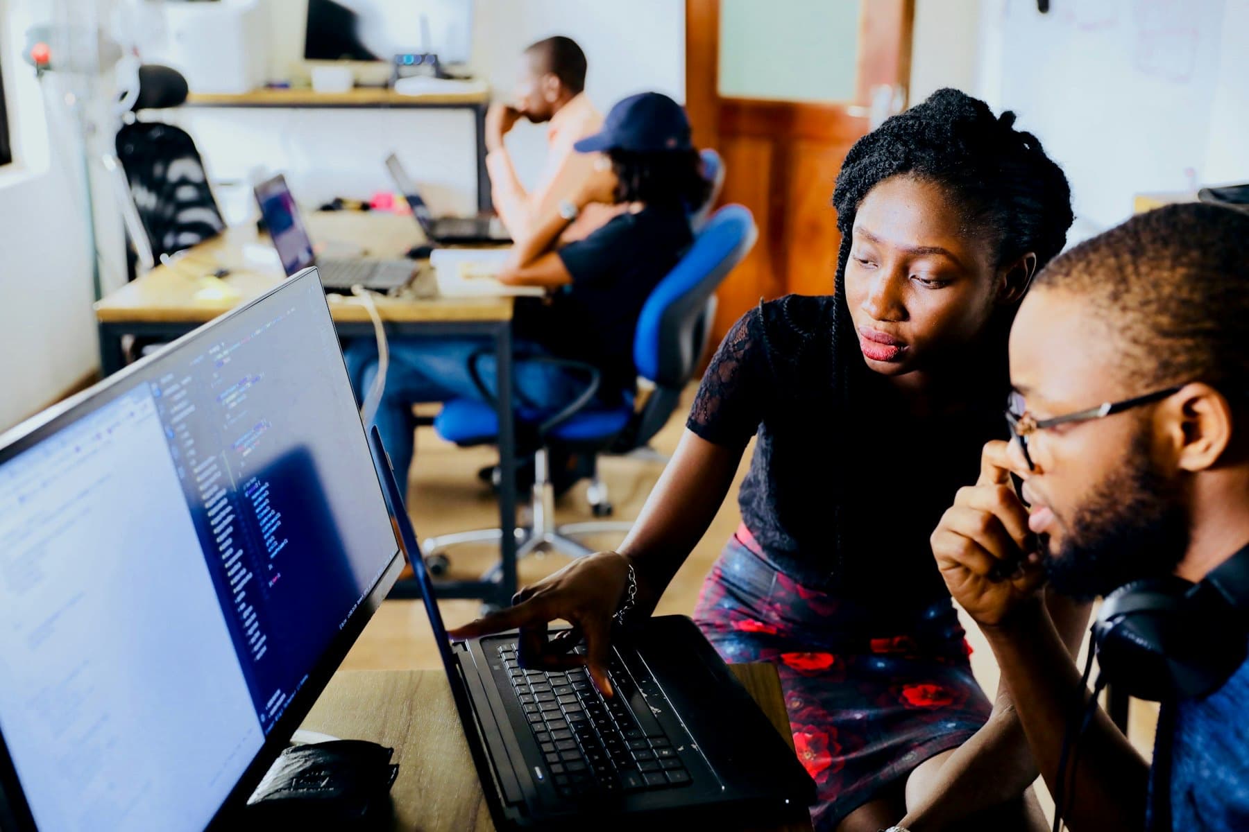 Engineers collaborating in front of a monitor showing code